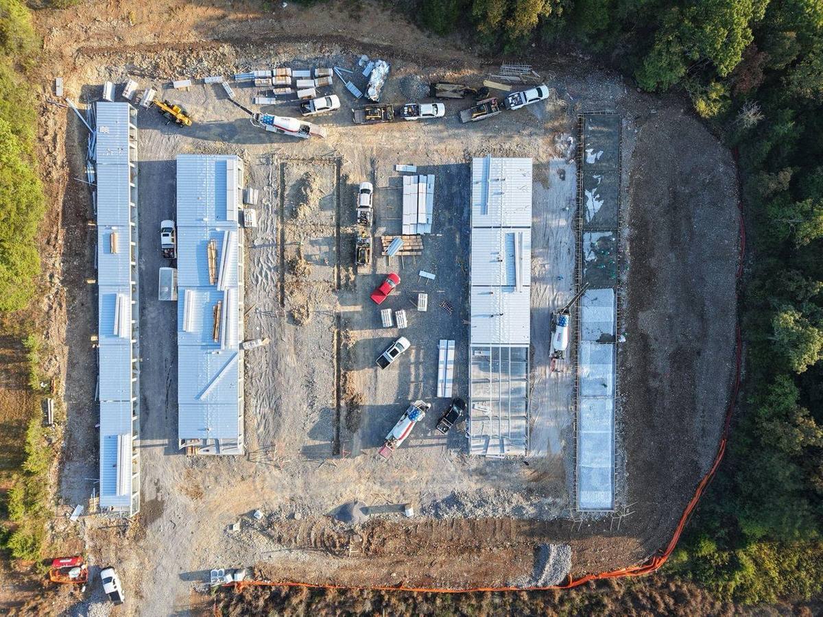 Top-down drone view with three buildings roofed and slabs ready for the others